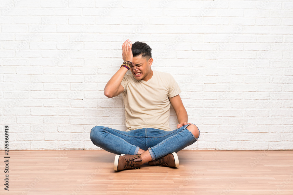 Young man sitting on the floor having doubts with confuse face expression Young man sitting on the floor having doubts with confuse face expression