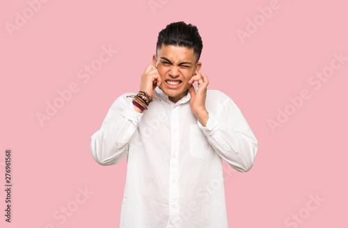 Young man frustrated and covering ears on colorful background