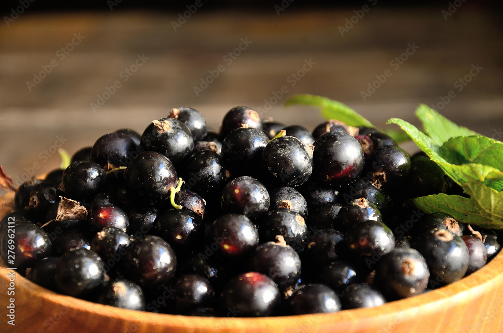 Harvest, ripe black currants, in a wooden bowl on old wooden boards. Harvest, ripe black currants, in a wooden bowl on old wooden boards.