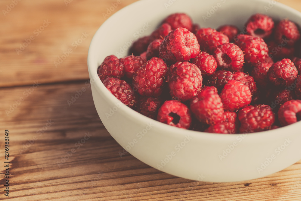 Fresh raspberries background closeup photo. Red raspberries in bowl on wooden table. Vintage style