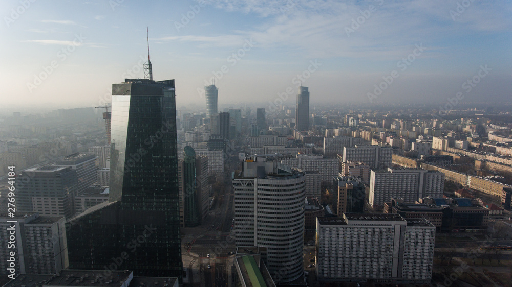 Obraz premium Downtown Warsaw skyline. Aerial view on modern skyscrapers in the fog. Modern skyscrapers are illuminated with the sure sun at sunset.
