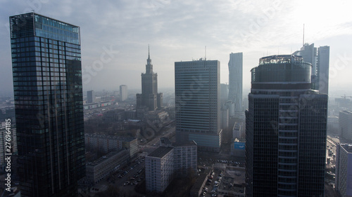 Downtown Warsaw skyline. Aerial view on modern skyscrapers in the fog. Modern skyscrapers are illuminated with the sure sun at sunset.