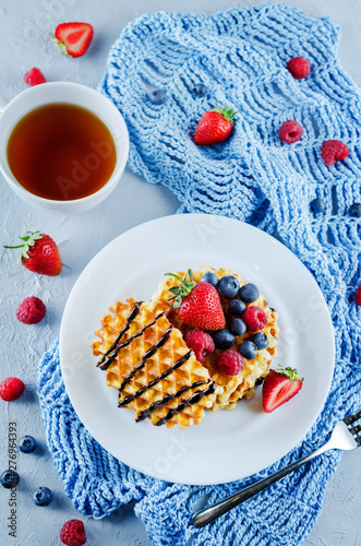 Waffeles with berries and mint leaf and a cup of tea