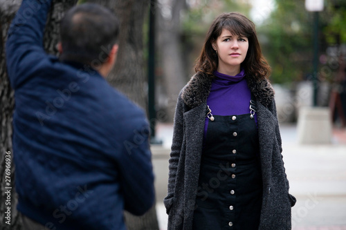 Man being rude, leering and cat calling or sexually harassing a woman walking on the street.  Also depicts crime and safety with a stalker following a female victim. photo