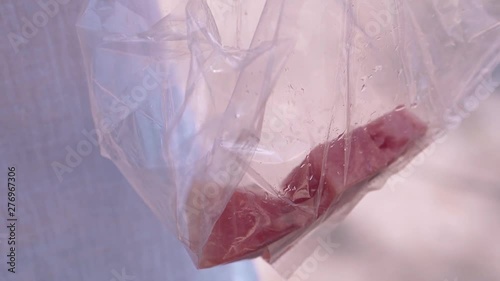 young woman hand takes ripe watermelon slice with bamboo chopstick from plastic bag close view photo