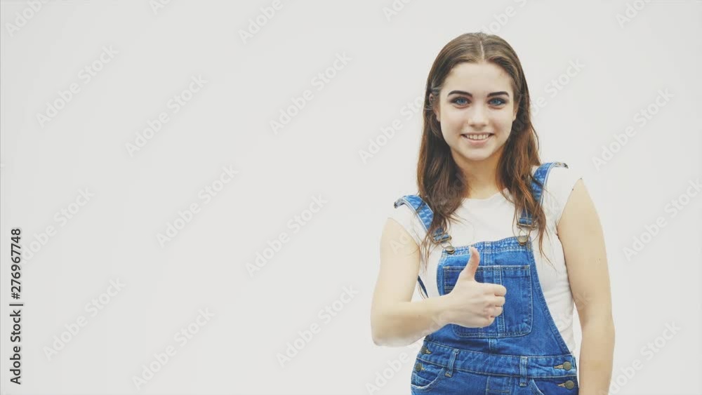Lovely girl looking to the side at something she likes and pointing her thumb up. Wavy hair woman, expressive facial expressions. Lovely girl looking to the side at something she likes and pointing her thumb up. Wavy hair woman, expressive facial expressions.
