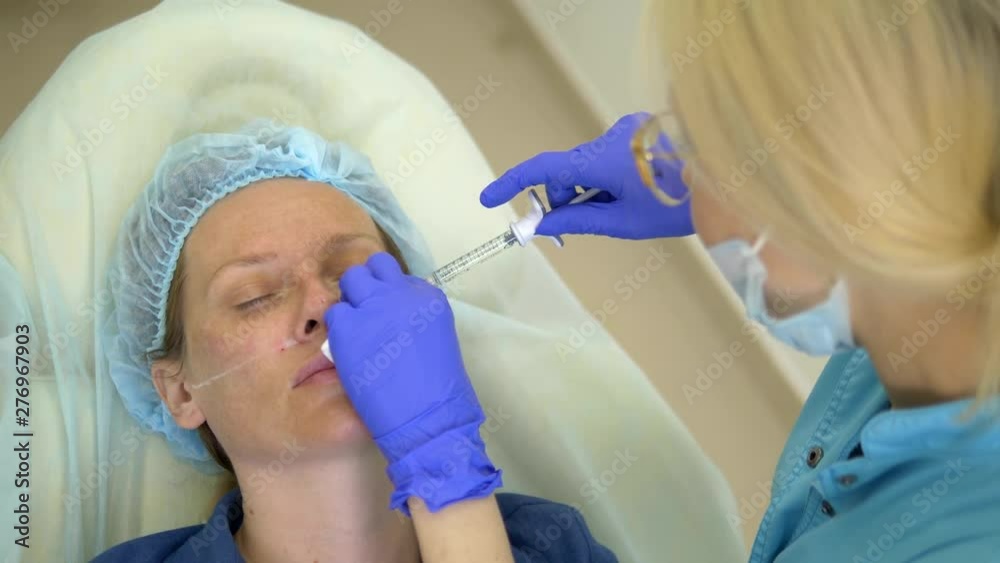 The concept of contour plastic face. A plastic surgeon injects a filler injection into the face of a woman. close-up. The concept of contour plastic face. A plastic surgeon injects a filler injection into the face of a woman. close-up.