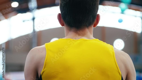 Athlete in yellow form preparing for performance. Back of man in sports shirt