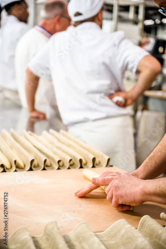 Baker rolls dough for French baguettes