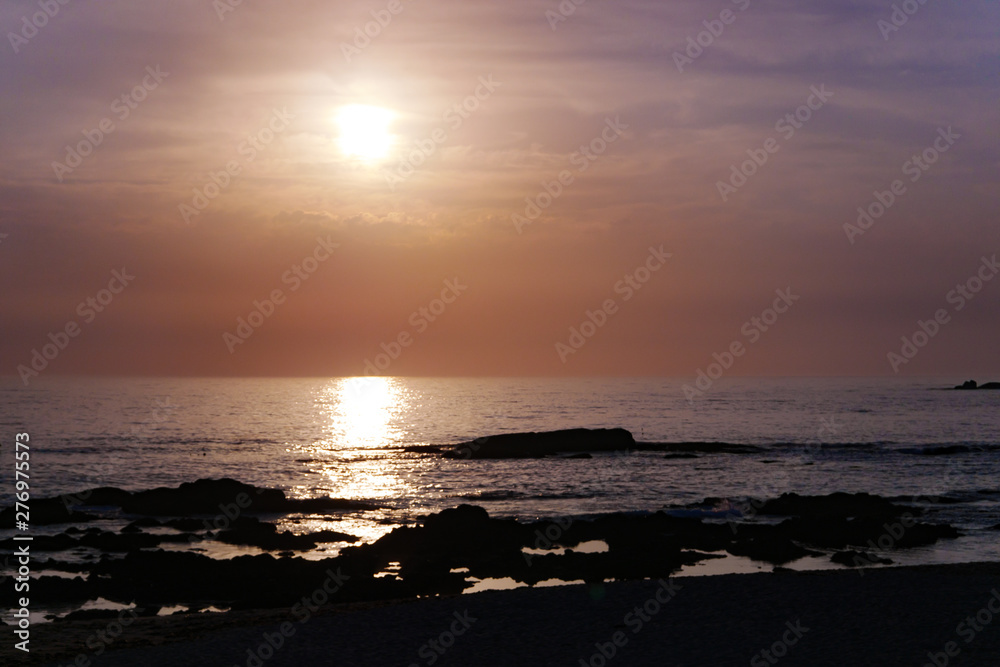 Sun reflected on ocean at sunset with pink sky