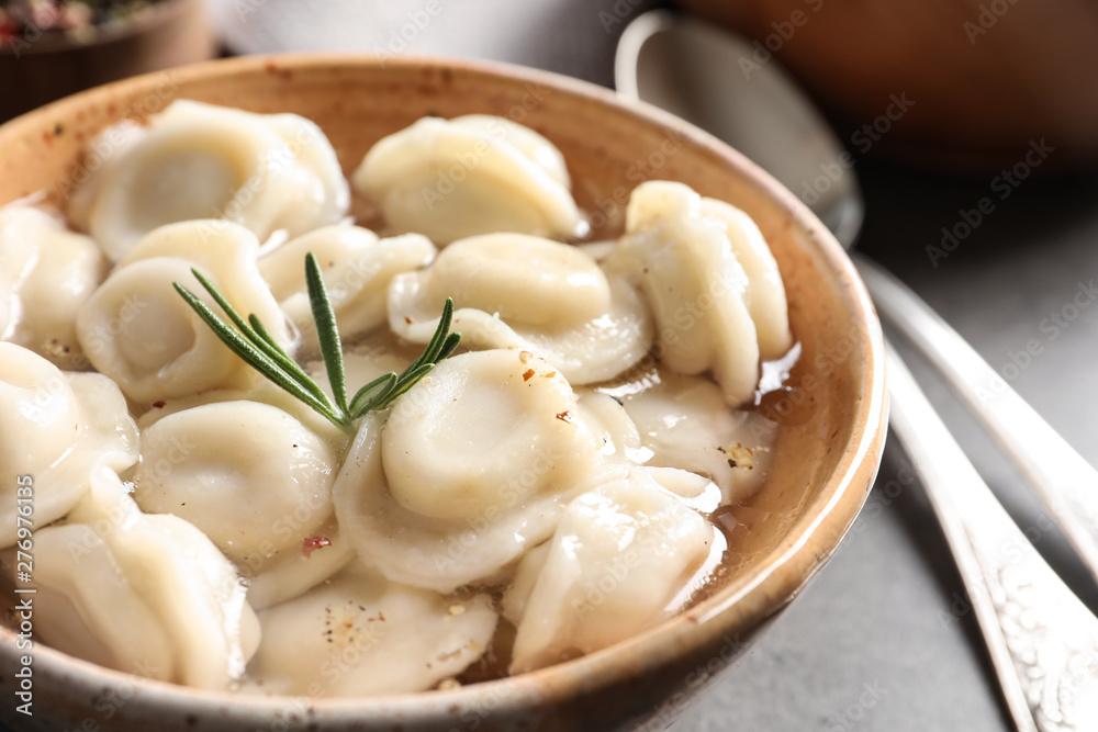 Bowl of tasty dumplings in broth on table, closeup Bowl of tasty dumplings in broth on table, closeup