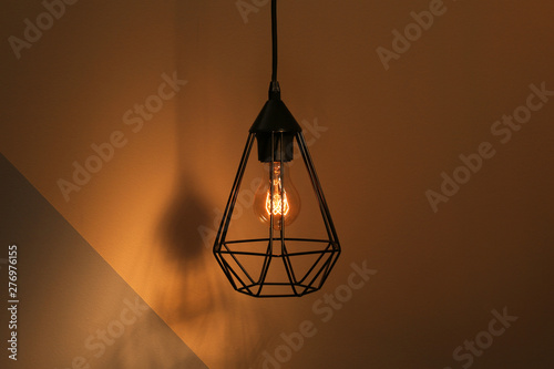 Hanging lamp bulb in chandelier against color background