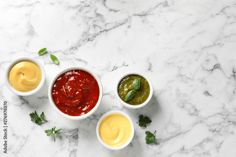 Set of different delicious sauces on white marble table, top view. Space for text Set of different delicious sauces on white marble table, top view. Space for text