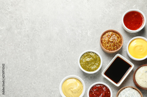 Set of different delicious sauces on grey table, top view. Space for text