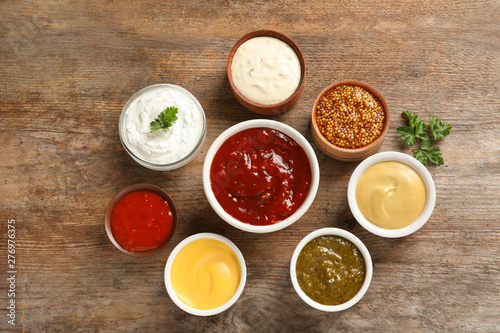 Set of different delicious sauces on wooden table, top view