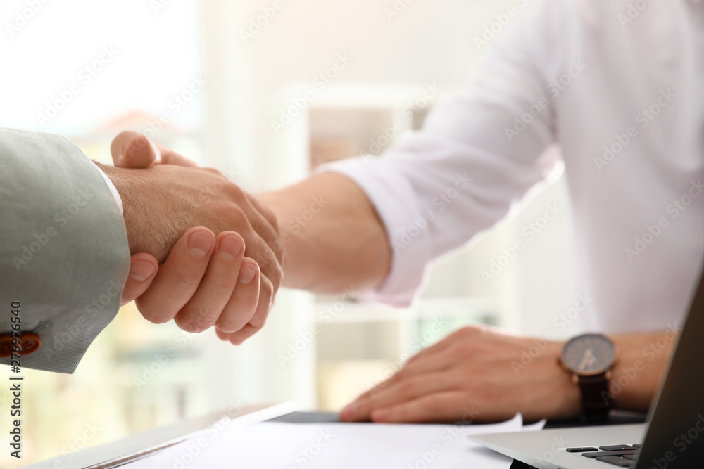 Business partners shaking hands at table after meeting in office, closeup Business partners shaking hands at table after meeting in office, closeup