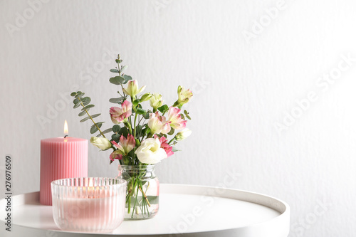 Fototapeta Naklejka Na Ścianę i Meble -  Stylish tender composition with burning candles and flowers on white table against light background, space for text. Cozy interior element
