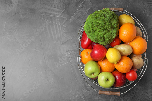 Basket with ripe fruits and vegetables on grey table  top view. Space for text