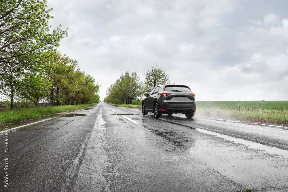 Wet suburban road with car on rainy day