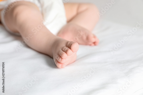 Little baby with cute feet on bed sheet, closeup. Space for text