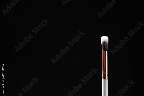 Eyeshadow makeup brush against dark background. Space for text