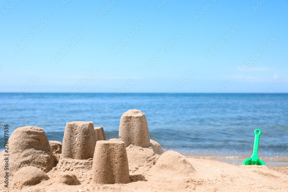 Little sand figures on beach near sea. Space for text