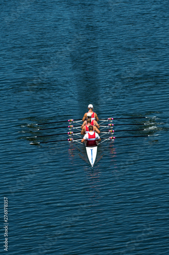 Four Male Rowers In A Quad Racing Boat With Synchronous Oar Stroke