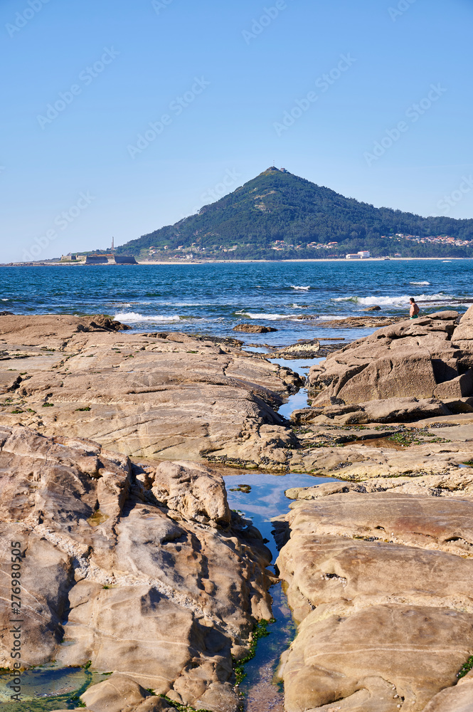 Rocks in front of the ocean bay with a mountain