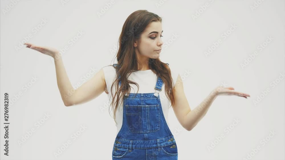 Young pretty lady with both of hands up, holding something, looking as if she is weighting two things, then choosing the thing in the left hand. Young pretty lady with both of hands up, holding something, looking as if she is weighting two things, then choosing the thing in the left hand.