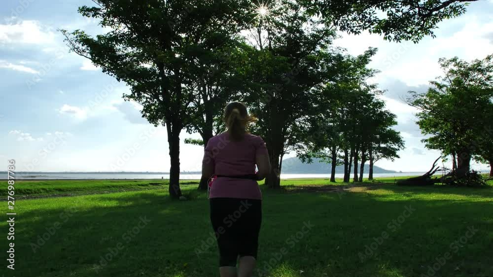 Asian women jogging in nature in the evening sunlight with the trees. Fitness and healthy lifestyle concept. Rear view of girl in sportswear running exercise. Slow motion Asian women jogging in nature in the evening sunlight with the trees. Fitness and healthy lifestyle concept. Rear view of girl in sportswear running exercise. Slow motion