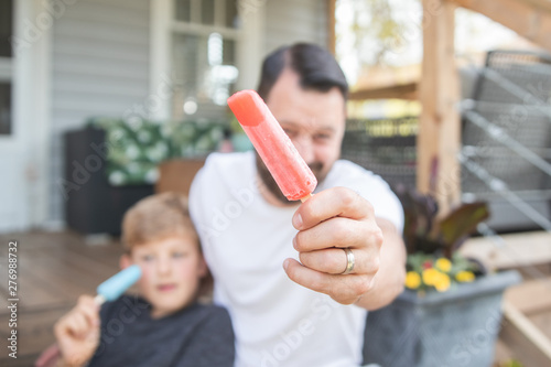 man holding ice pop on a porch in summer