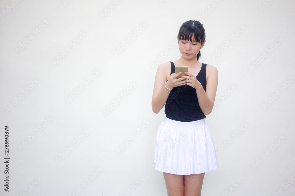 Portrait of thai adult beautiful girl black shirt white skirt using her smart phone Portrait of thai adult beautiful girl black shirt white skirt using her smart phone