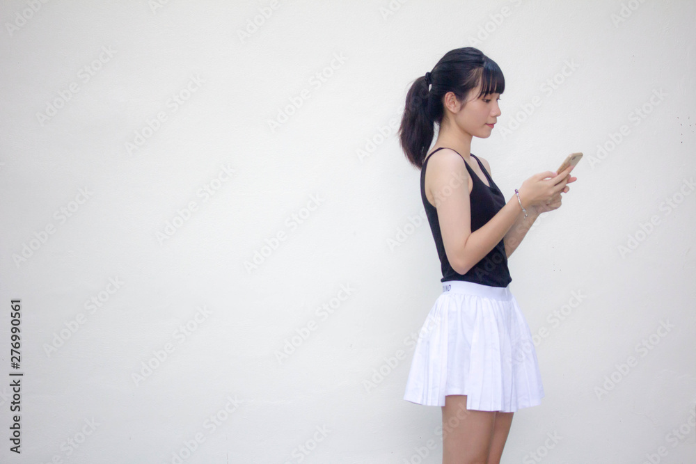 Portrait of thai adult beautiful girl black shirt white skirt using her smart phone Portrait of thai adult beautiful girl black shirt white skirt using her smart phone