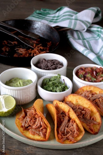 tacos with pork long languor and different sauces, salsa, guacamole, ketchup, cilantro. fried tortilla cakes