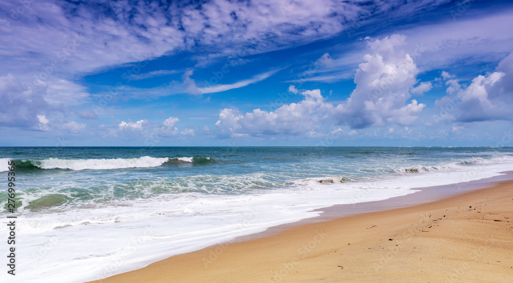Beautiful Tropical sandy beach with blue ocean and blue sky background and wave crashing on sandy shore