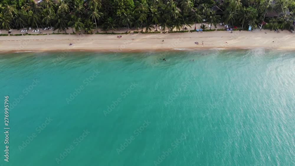 Blue lagoon and sandy beach with palms. Aerial view of blue lagoon and sun beds on sandy beach with coconut palms and roof bungalows Blue lagoon and sandy beach with palms. Aerial view of blue lagoon and sun beds on sandy beach with coconut palms and roof bungalows
