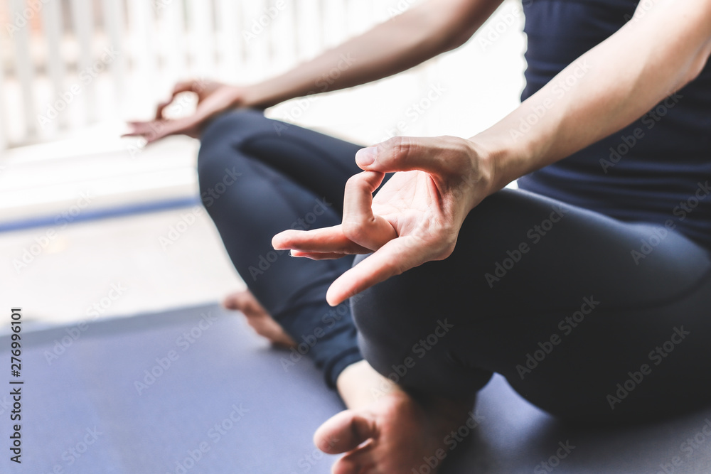 Young woman practicing yoga in  gray background.Young people do yoga indoor.Close up hands in meditating gesture. Copy space.