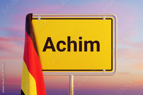 Achim. Gelbes Schild/Ortsschild. Flagge von Deutschland hängt darüber. Himmel mit Sonnenuntergang oder Sonnenaufgang photo