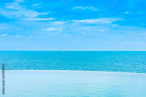 Beautiful outdoor infinity swimming pool in hotel resort with sea ocean view and white cloud blue sky