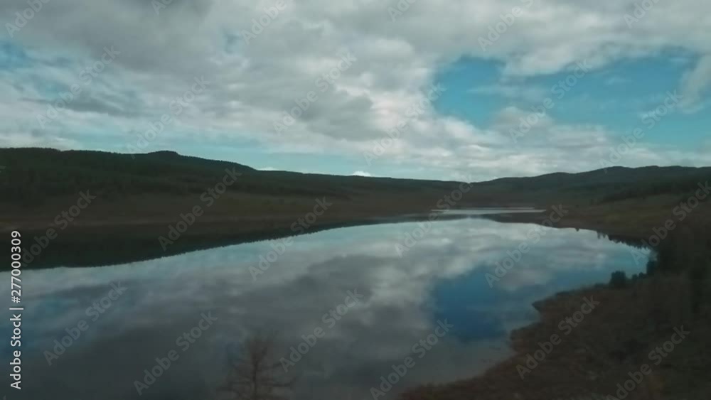 Aerial view of mountain lake with beautiful clouds reflected in a water surfac. coniferous forest on the shore Aerial view of mountain lake with beautiful clouds reflected in a water surfac. coniferous forest on the shore