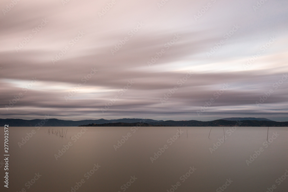 Beautiful long exposure view of Trasimeno Lake (Umbria, Italy), with still water and moving clouds