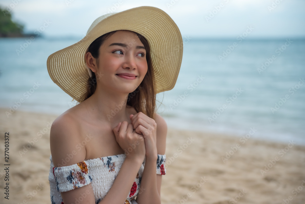 Summer beach vacation concept, Happy young Asian woman with hat walking and relaxing on sand beach with happiness.