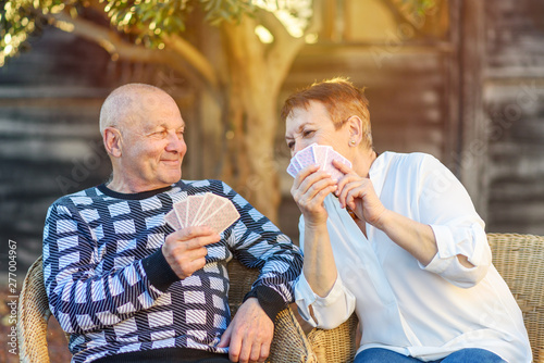 Quadro em tela Senior couple playing cards game at park on sunny day