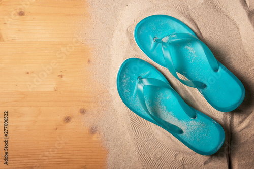 Summer holiday background with blue flip flops on wood panel, top view with copy space