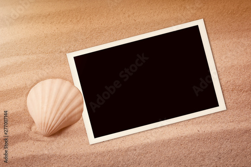 Empty photo card lying on a sea sand. Sunny summer background.