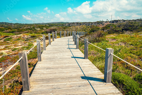 Fototapeta Naklejka Na Ścianę i Meble -  The wooden stairway at the rocky seashore on a sunny day. Polvoeira the beach. Pataias, Portugal, Europe