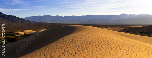Sand dunes in a desert landscape in Death Valley California.  The vast barren land is dry and arid due to droughts result of global warming and climate change.