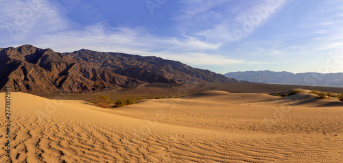 Sand dunes in a desert landscape in Death Valley California.  The vast barren land is dry and arid due to droughts result of global warming and climate change.