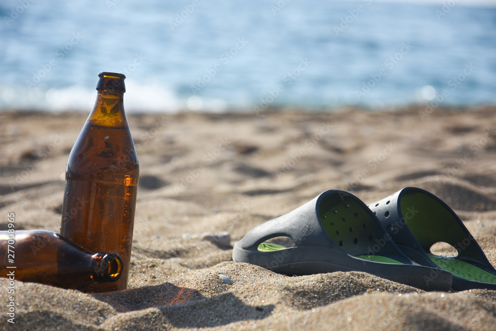 Obraz premium Cold beer and slippers on sand at beach. Summer vacation concept, enjoy at beach