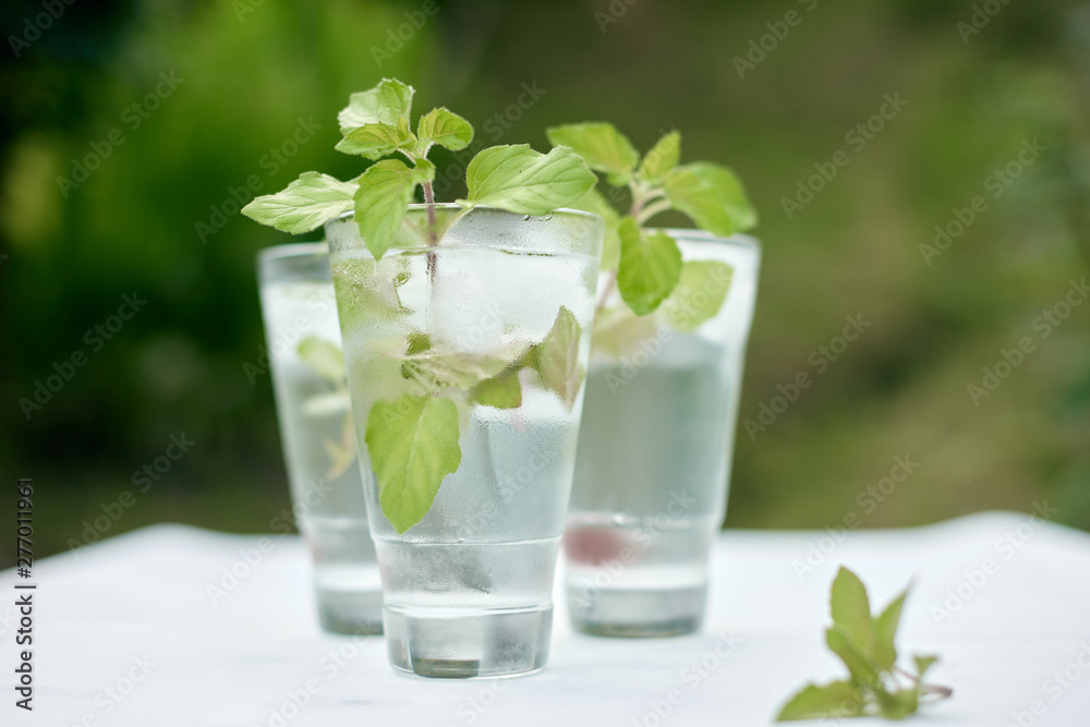 Summer hot fresh drink with mint in glass on white green grey background Summer hot fresh drink with mint in glass on white green grey background